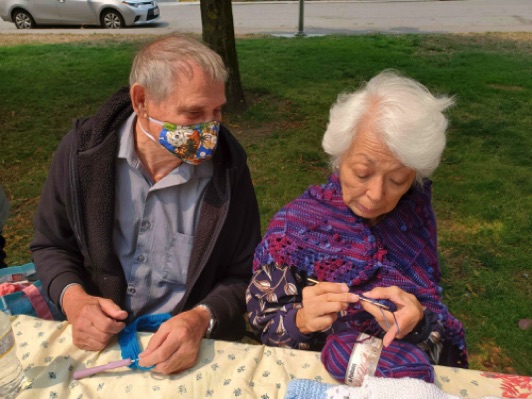 Wayne and Chiz share crocheting tips in the Knitting Group.